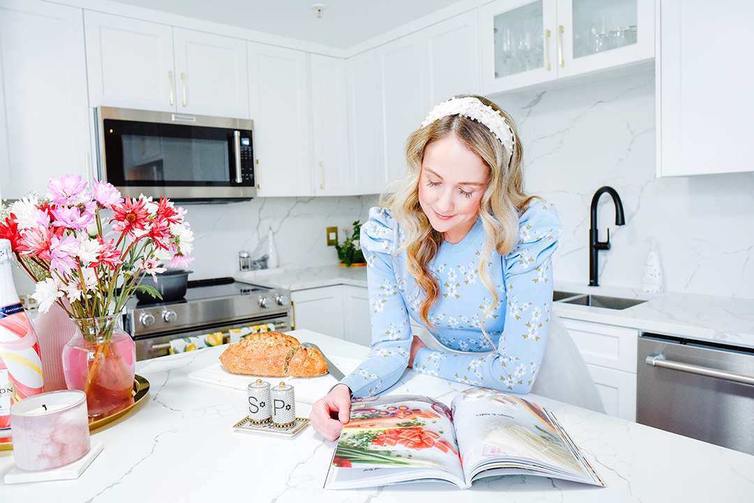 Halifax blogger poses reading a cook book and fresh bread in her newly renovated kitchen