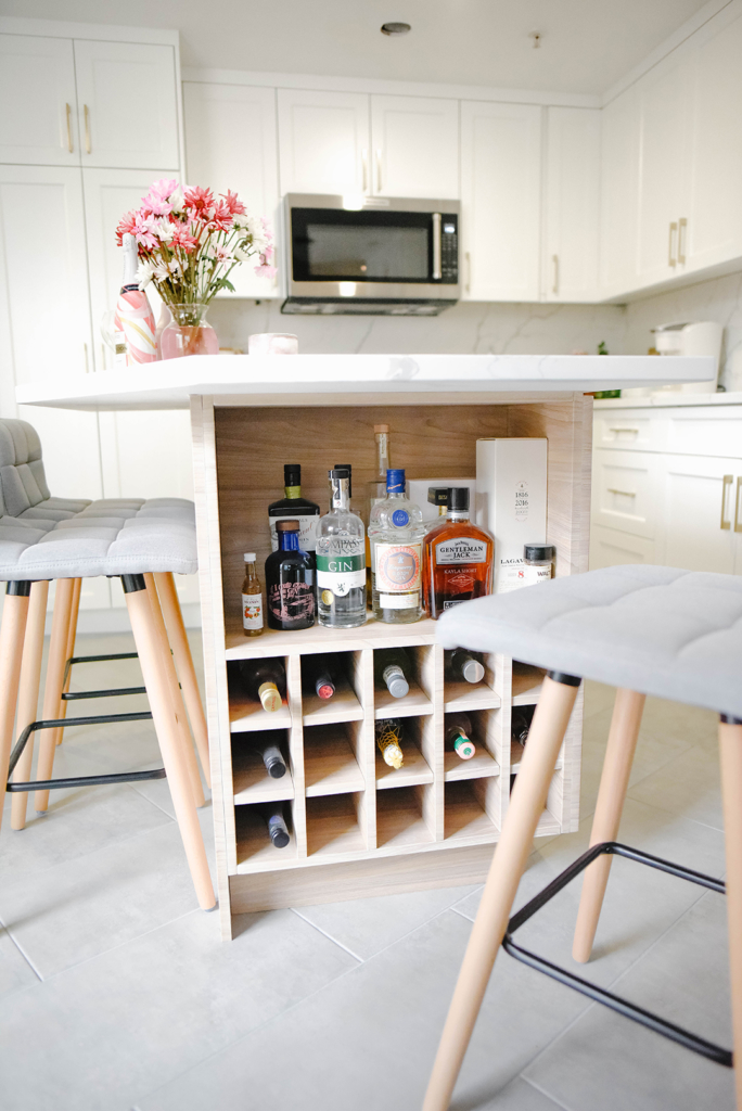 Gray tile flooring sits beneath a kitchen island with wine storage and stools