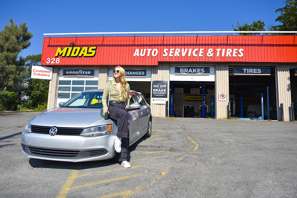 Halifax Blogger Kayla Short sits on car in front of Midas Auto Service Shop 